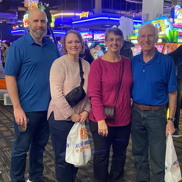 Four smiling adults standing together inside an arcade