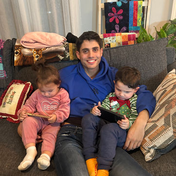 A young man sitting on a couch with two young children