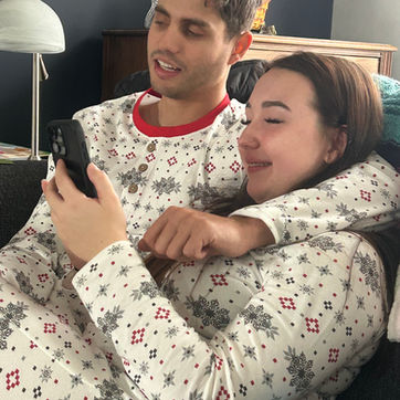 A smiling young couple in matching snowflake pajamas taking a selfie